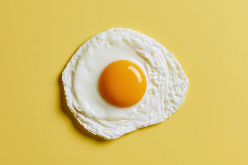 Single fried egg centered overhead on yellow background