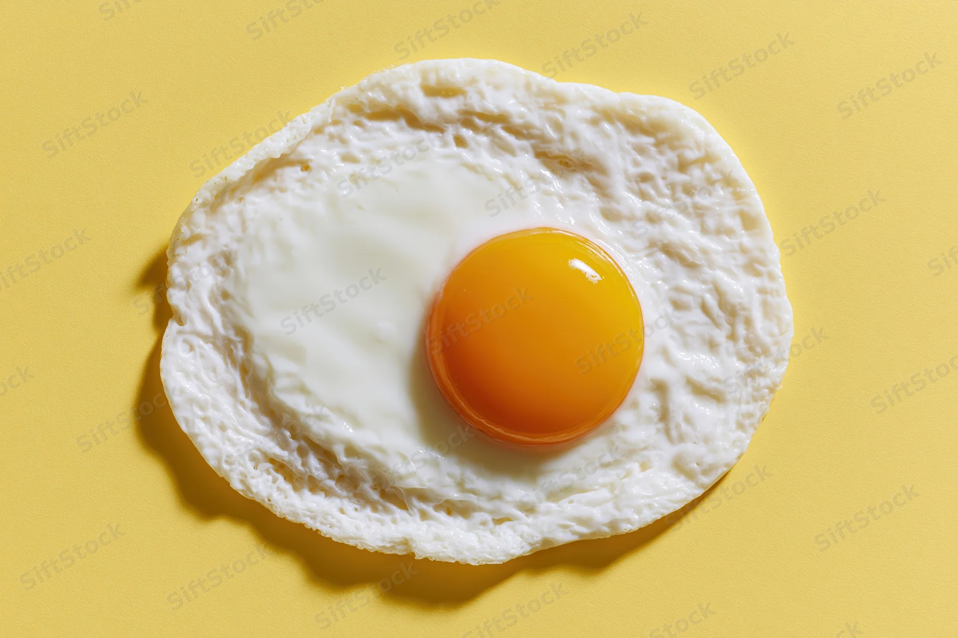 Single fried egg centered overhead on yellow surface