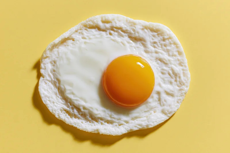 Single fried egg centered overhead on yellow surface
