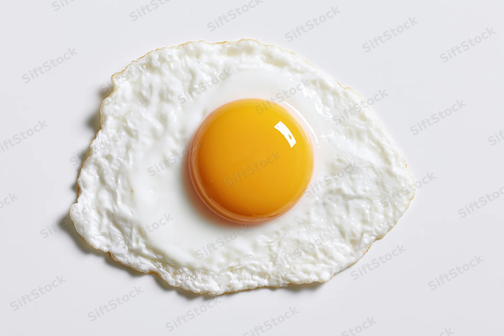 Single fried egg sunny side up on white surface overhead view