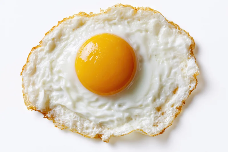 Single fried egg sunny-side up on plain white background