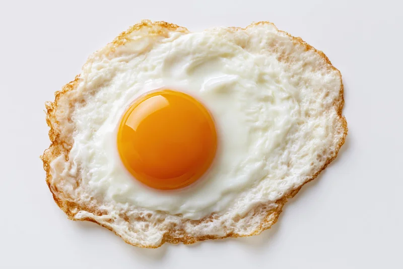 Single fried egg sunny-side up on plain white surface