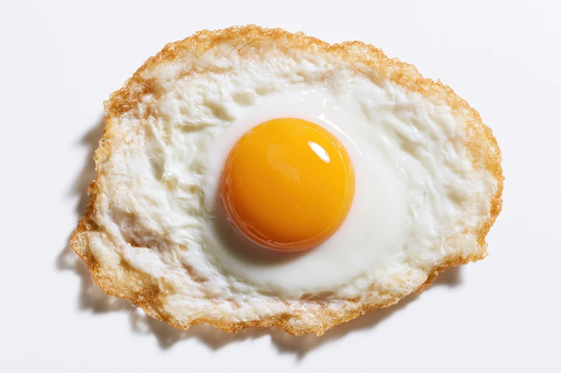 Single fried egg sunny-side up on plain white background