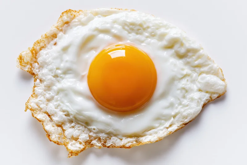 Single fried egg sunny-side up on plain white surface