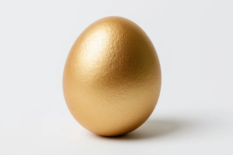Single gold-painted egg standing upright centered against a white background