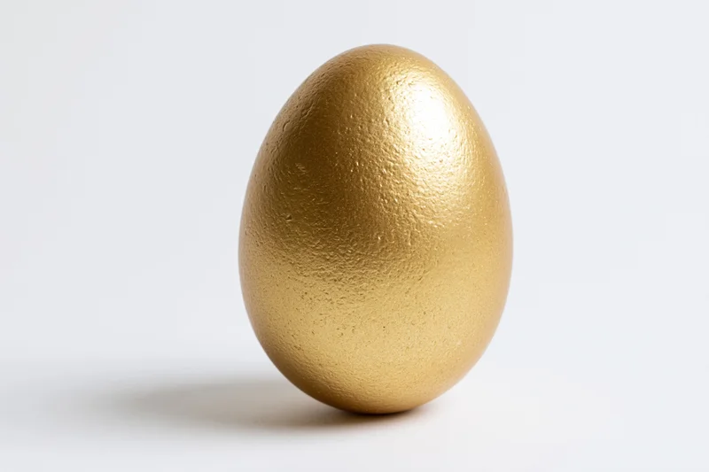 Golden painted egg standing upright isolated on white background