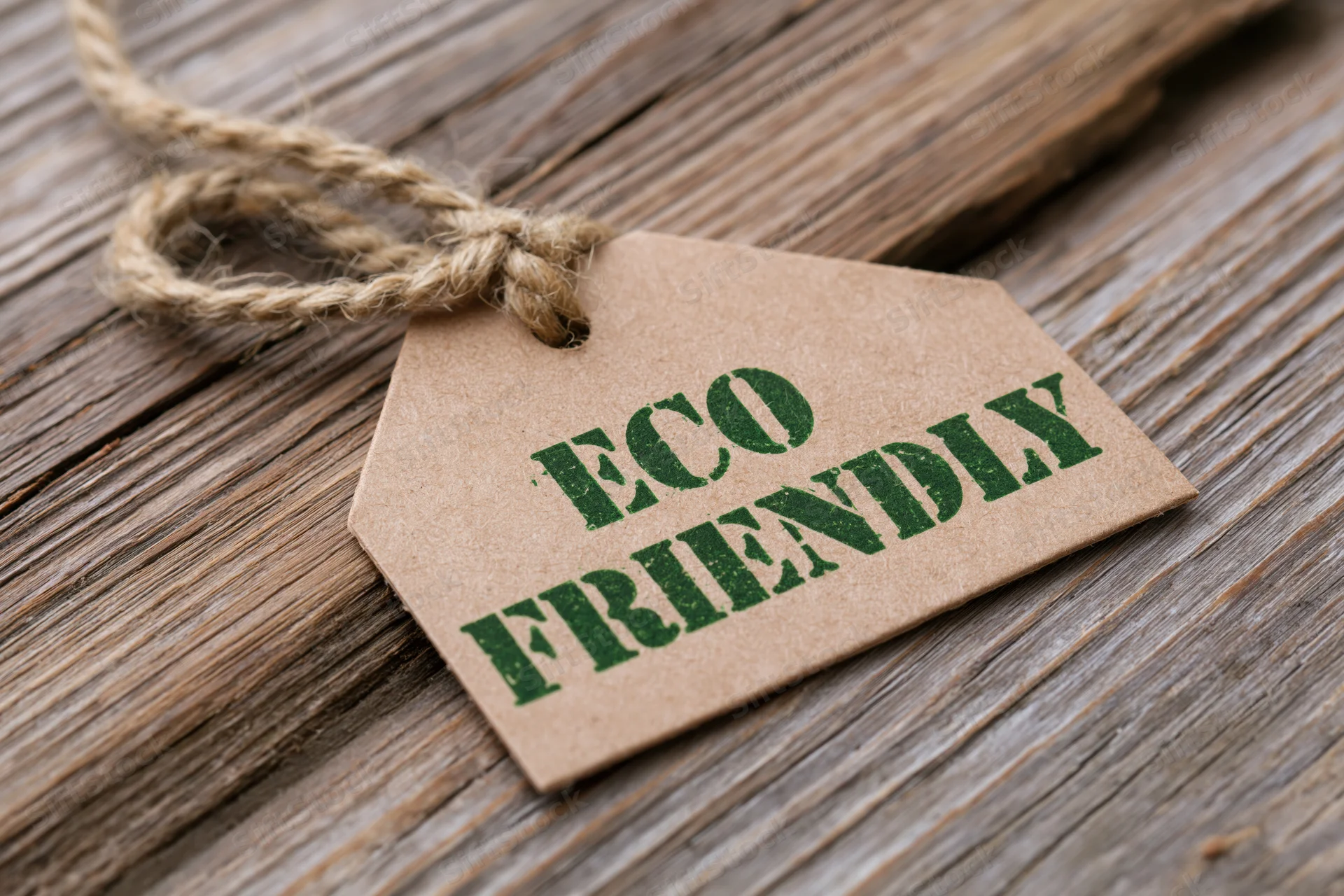 Kraft paper tag with eco friendly text tied with twine on wooden surface
