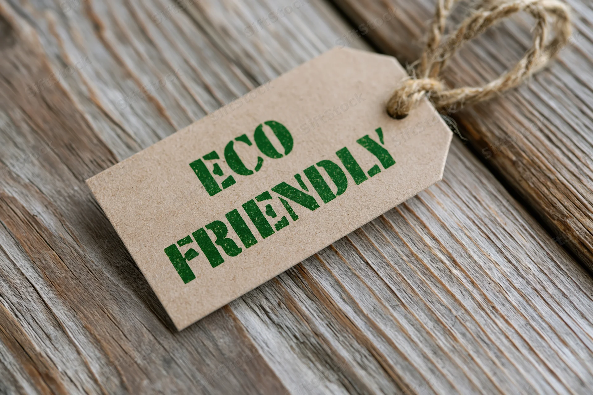 Kraft paper tag with eco friendly text printed in green on wooden surface tied with twine