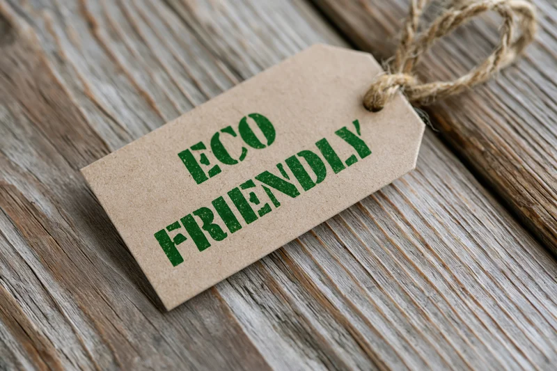 Kraft paper tag with eco friendly text printed in green on wooden surface tied with twine