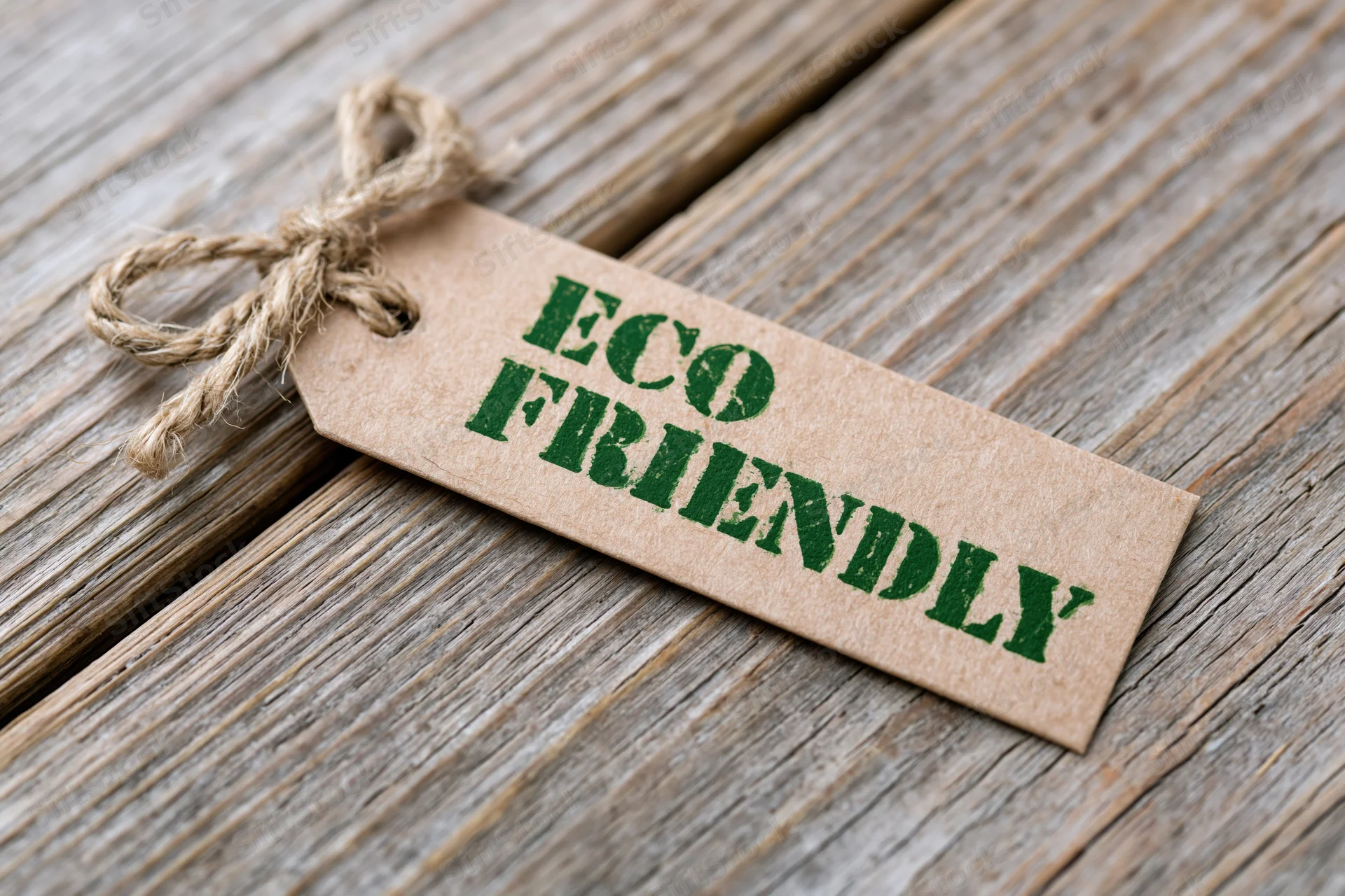 Kraft paper tag with eco friendly text tied with twine on wooden surface