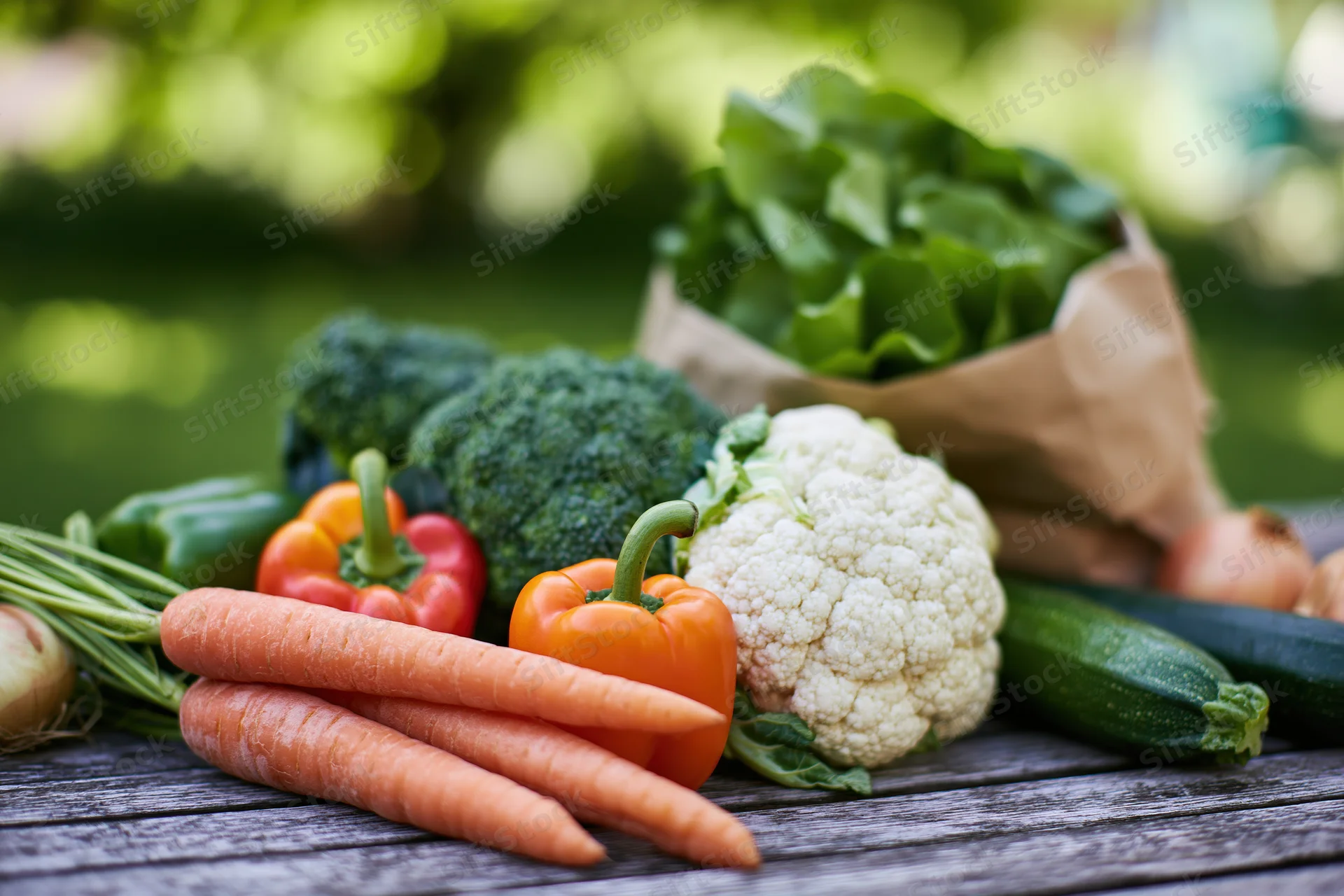 Assorted fresh vegetables arranged on a weathered wooden table outdoors