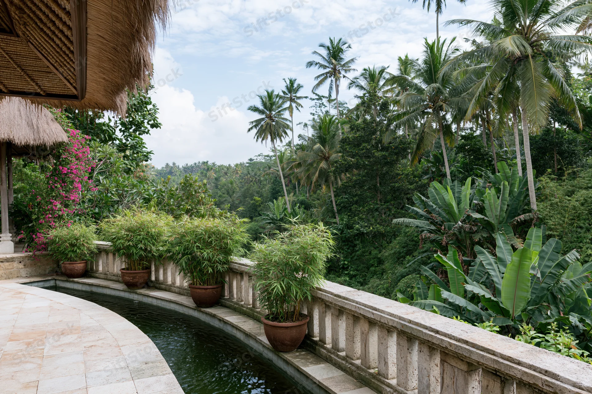 Balinese villa terrace with curved infinity-edge pond and tropical garden overlooking jungle landscape