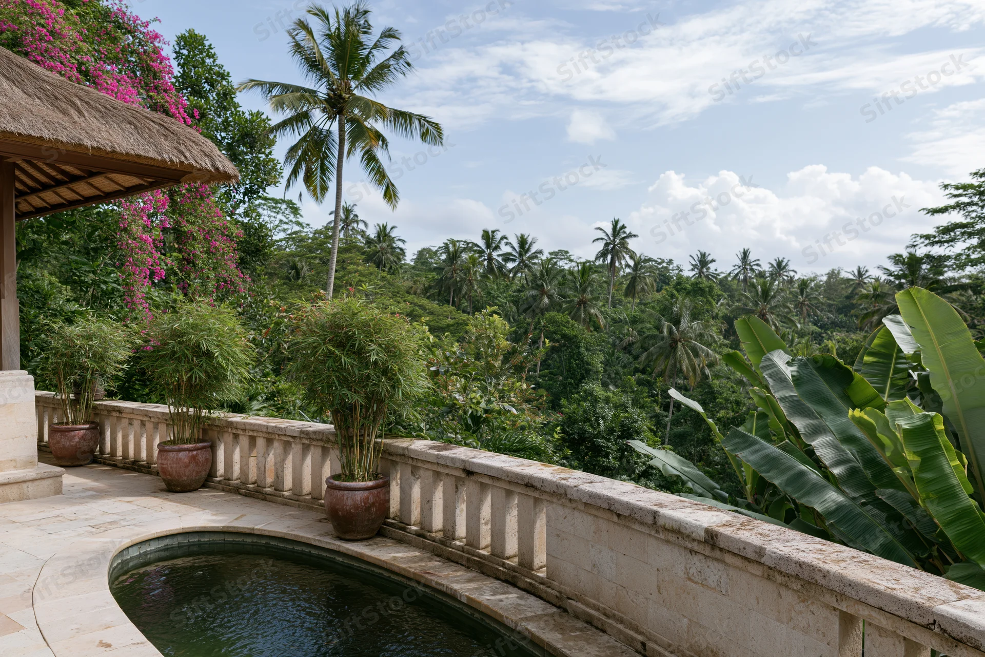 Balinese villa terrace with curved infinity-edge pond overlooking tropical jungle and palm trees