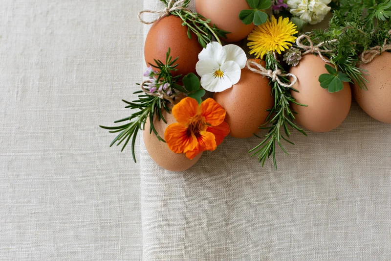 Brown eggs decorated with wildflowers and herbs arranged on a linen cloth