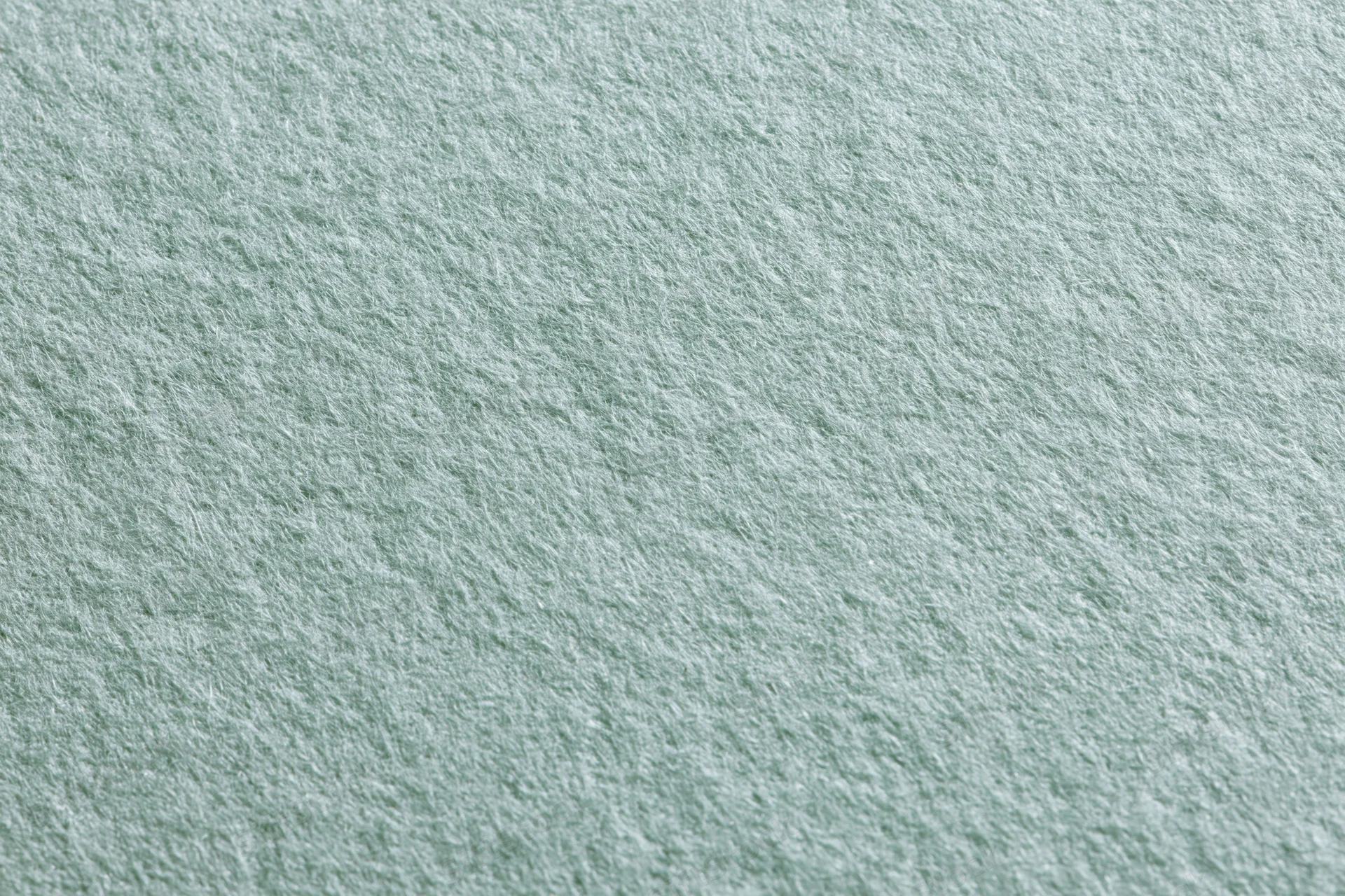 Close-up flat lay of pale sage green paper surface with visible texture