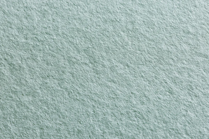 Close-up flat lay of pale sage green paper surface with visible texture
