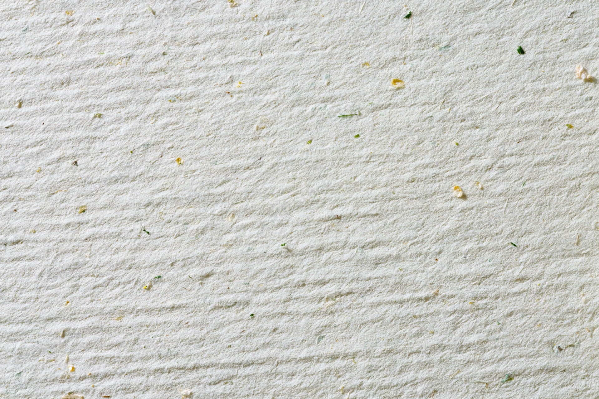 Close-up flat lay of a sheet of off-white recycled paper with visible plant fibers and texture