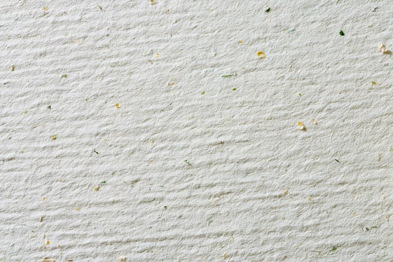 Close-up flat lay of a sheet of off-white recycled paper with visible plant fibers and texture