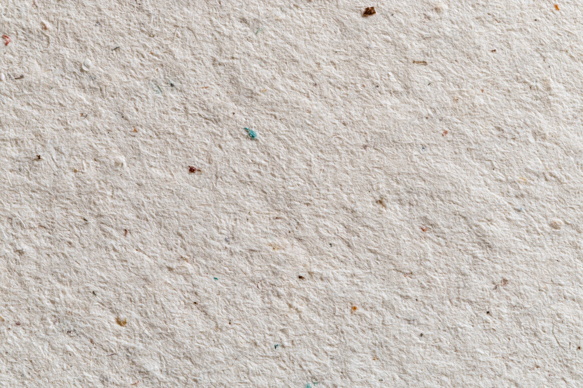 Close-up flat lay of a textured sheet of recycled kraft paper with visible fibers and speckles