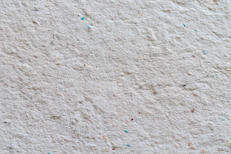Close-up flat lay of a textured recycled cardboard sheet with colored flecks scattered across its surface