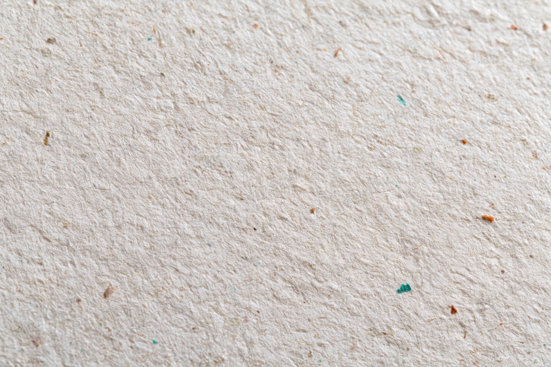 Close-up flat lay of textured recycled paper surface with colored fiber specks
