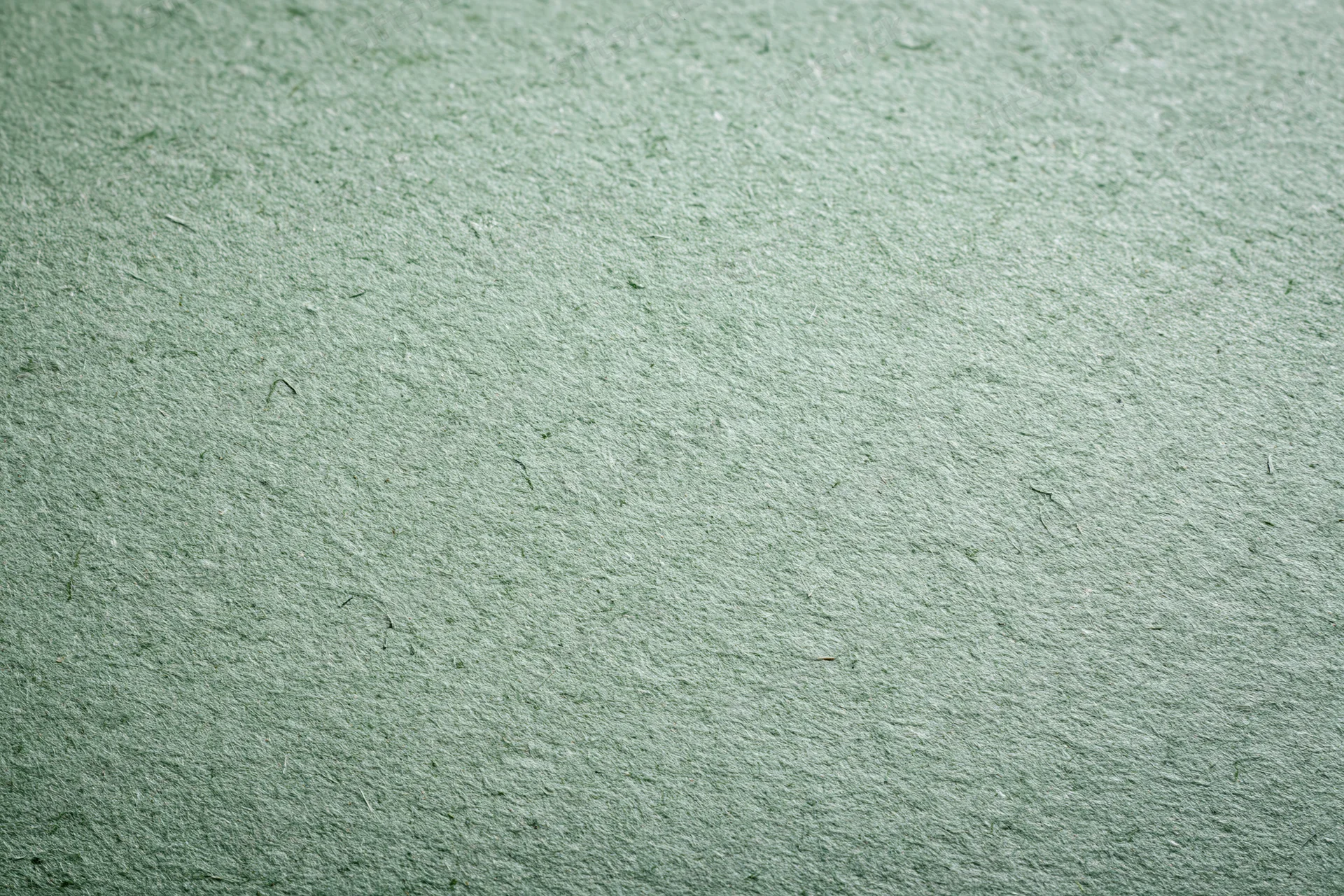 Close-up flat lay of a sheet of recycled green paper filling the frame with textured surface