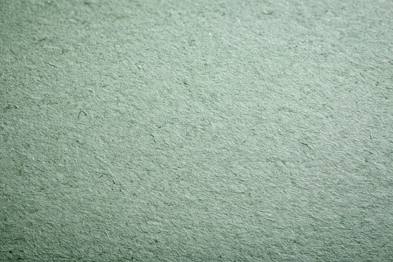 Close-up flat lay of a sheet of recycled green paper filling the frame with textured surface