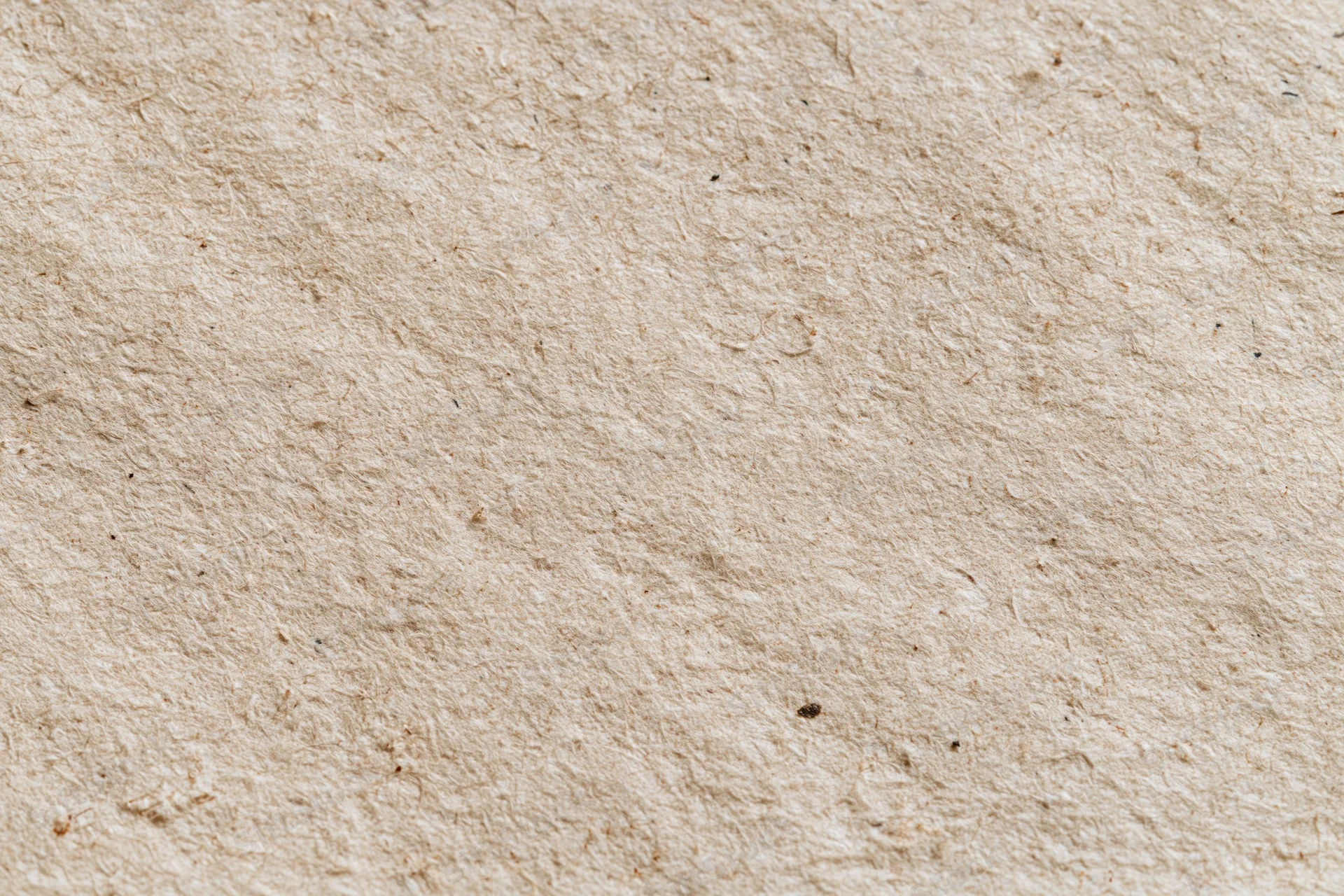 Close-up flat lay of a sheet of recycled kraft paper filling the frame with visible fibers and natural texture