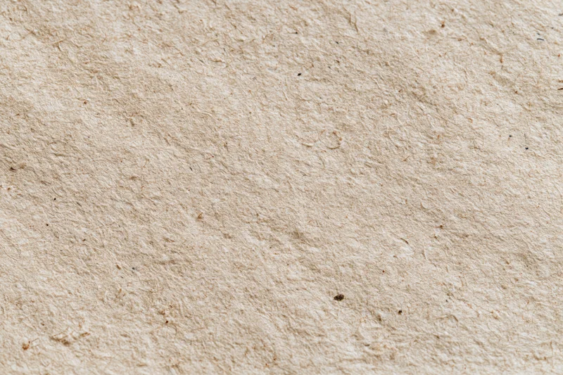 Close-up flat lay of a sheet of recycled kraft paper filling the frame with visible fibers and natural texture