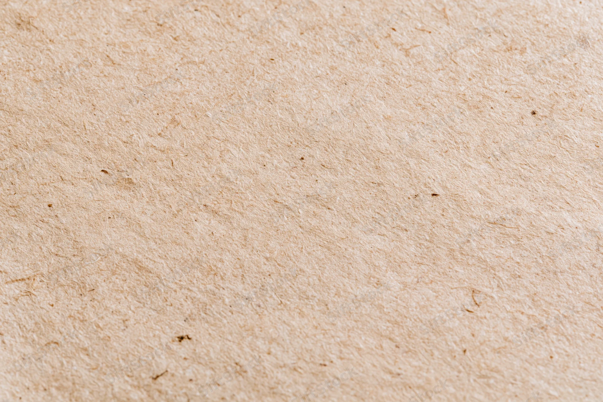 Close-up flat lay of a sheet of recycled kraft paper filling the frame with visible fibers and natural texture