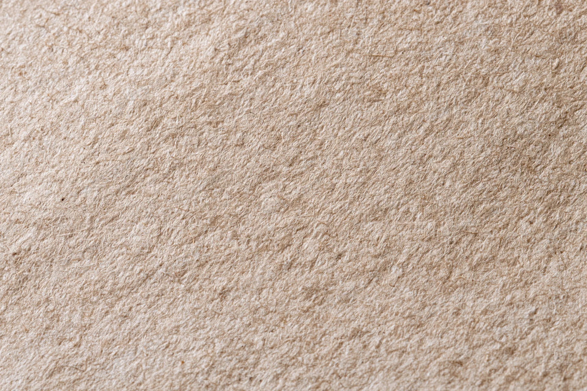 Close-up flat lay of recycled kraft paper with linen-like texture filling the frame