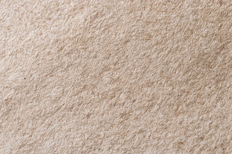 Close-up flat lay of recycled kraft paper with linen-like texture filling the frame