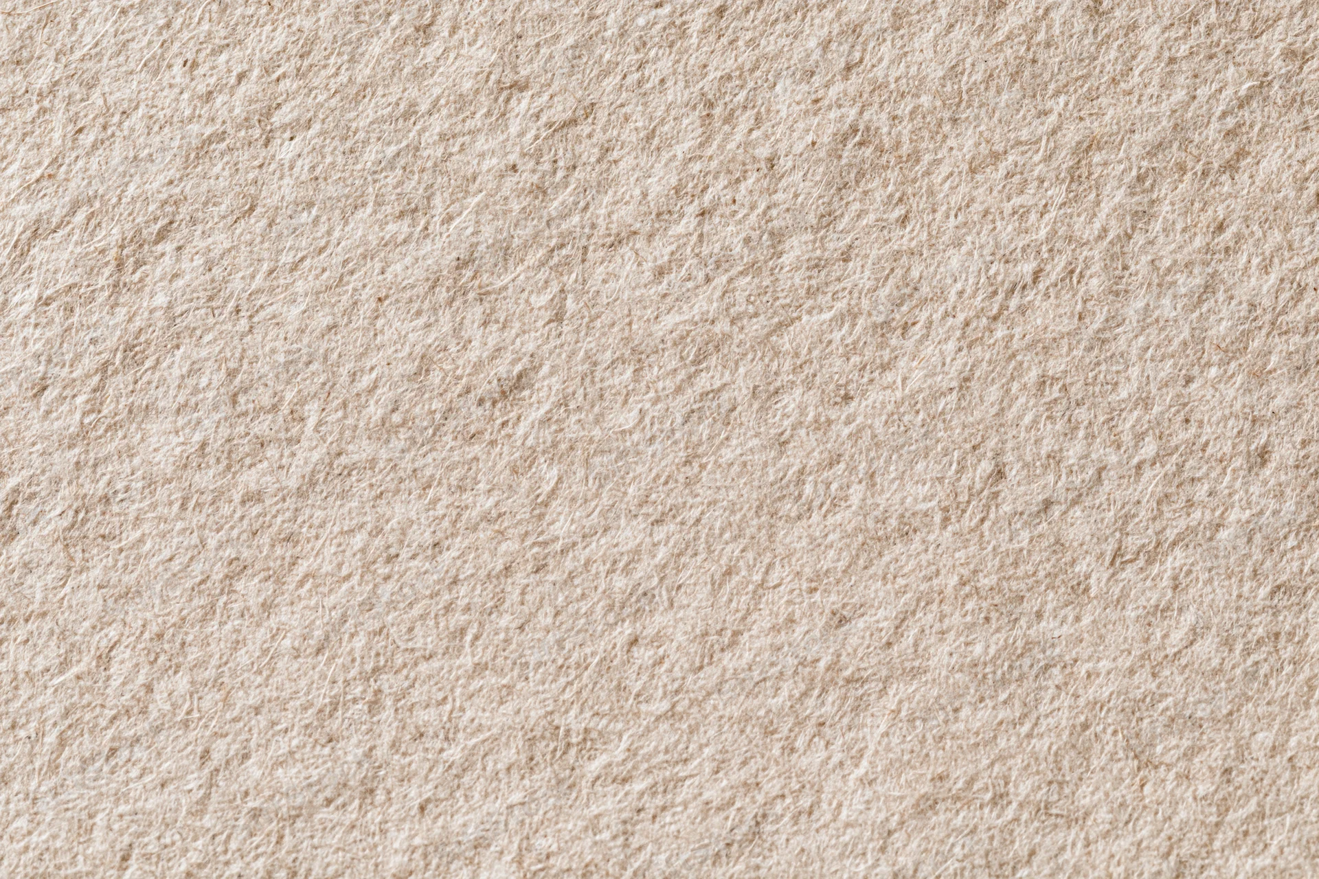 Close-up flat lay of recycled kraft paper with linen-like texture and natural beige tone