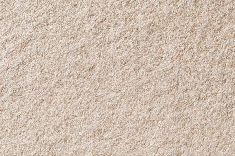 Close-up flat lay of recycled kraft paper with linen-like texture and natural beige tone