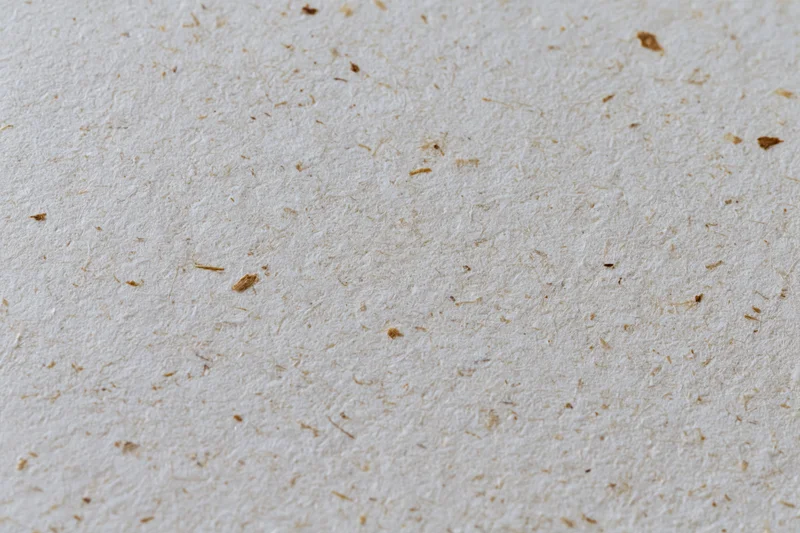 Close-up flat lay of recycled kraft paper surface filling the frame with visible fibers and speckles