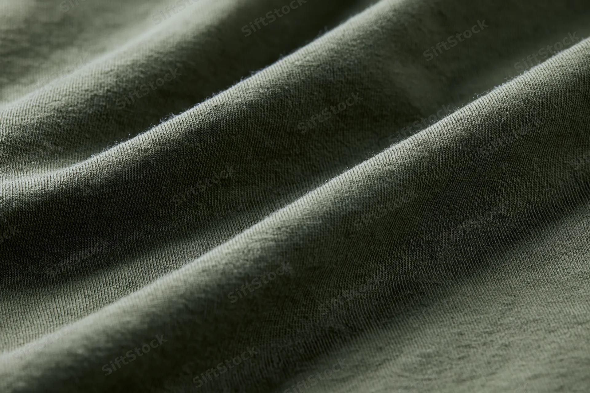 Close-up of dark olive green cotton jersey fabric with visible knit texture and soft folds