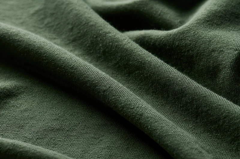 Close-up of dark olive green cotton jersey fabric with folds and texture