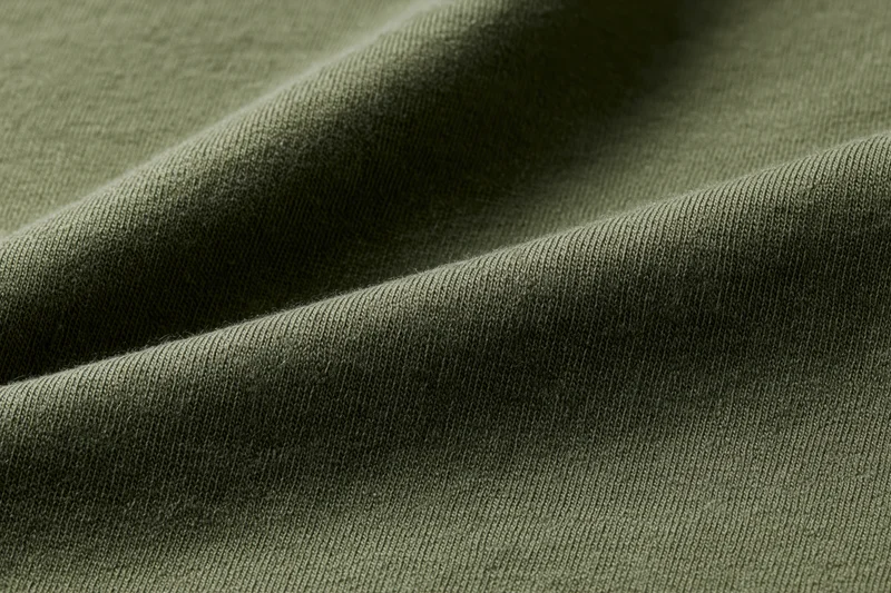 Close-up of dark olive green cotton jersey fabric with visible knit texture and folds