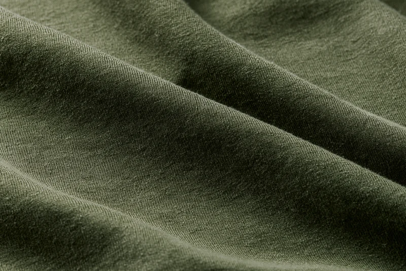 Close-up of dark olive green cotton jersey fabric showing texture and weave