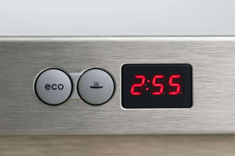 Close-up of a dishwasher control panel with two grey buttons and a red digital timer display showing 2:55