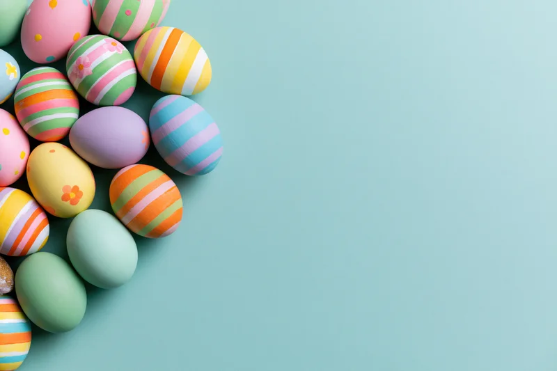 Colorful hand-painted easter eggs arranged in a loose cluster on a teal background with copyspace