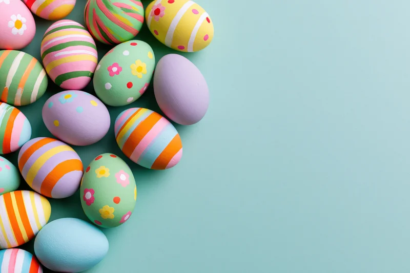 Colorful hand-painted easter eggs arranged in a loose cluster on a pastel blue background with copyspace