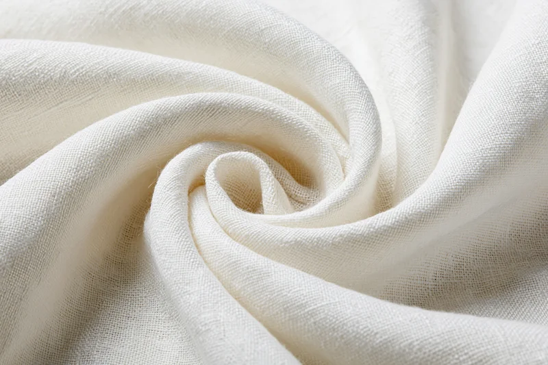Cream-white linen fabric draped in soft flowing folds forming a swirl pattern