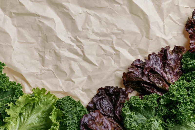 Fresh leafy vegetables arranged on crumpled kraft paper background