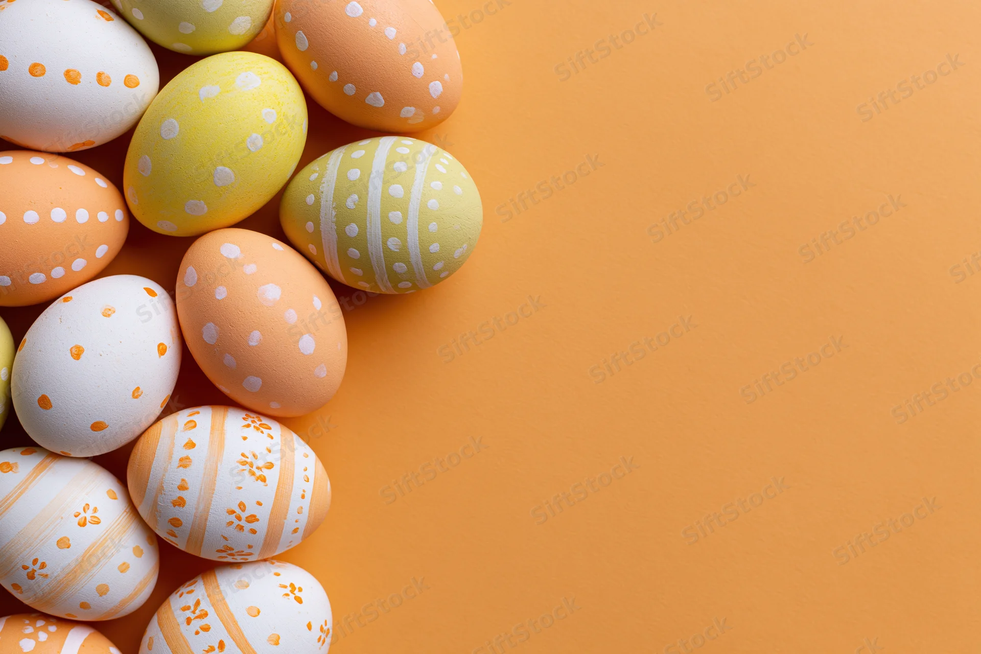 Decorated easter eggs arranged in a loose vertical cluster on orange background with copyspace
