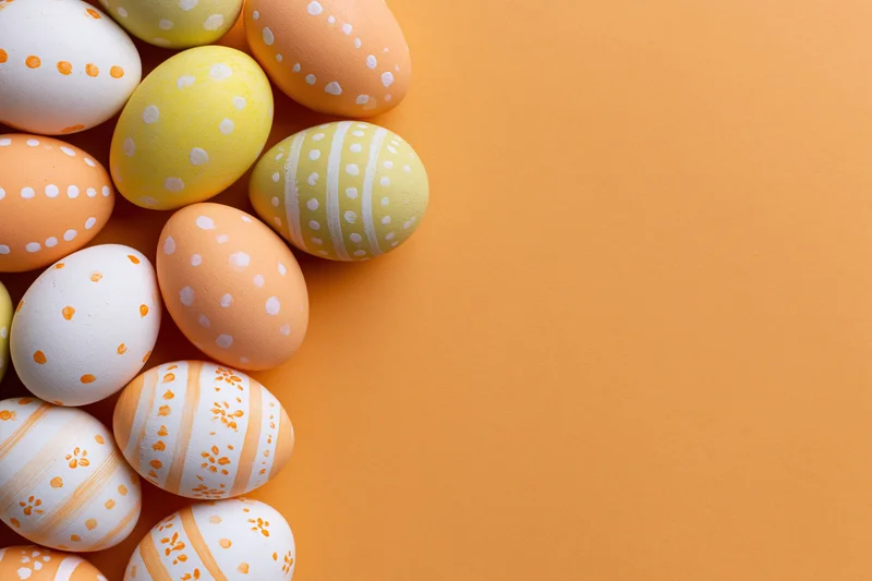 Decorated easter eggs arranged in a loose vertical cluster on orange background with copyspace