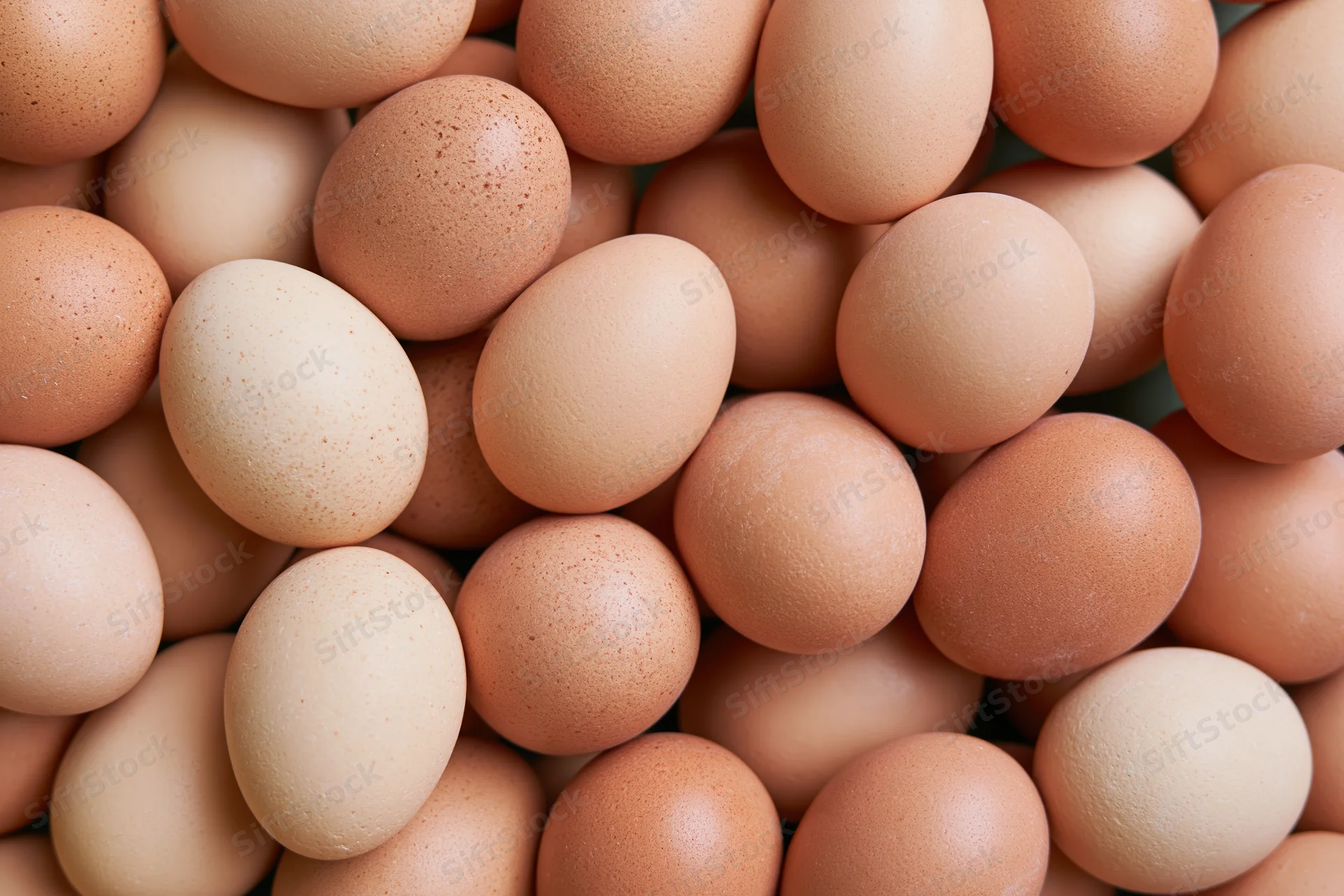 Brown chicken eggs piled loosely filling the frame