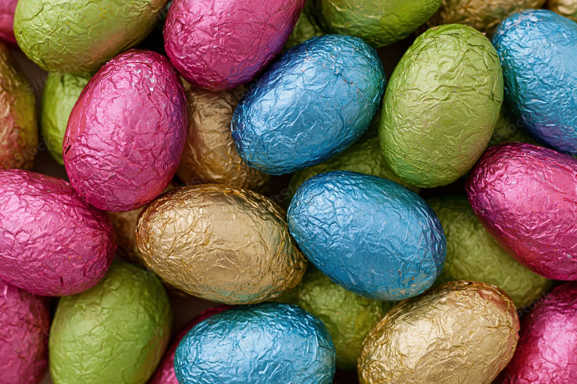 Foil-wrapped chocolate easter eggs piled together in closeup view