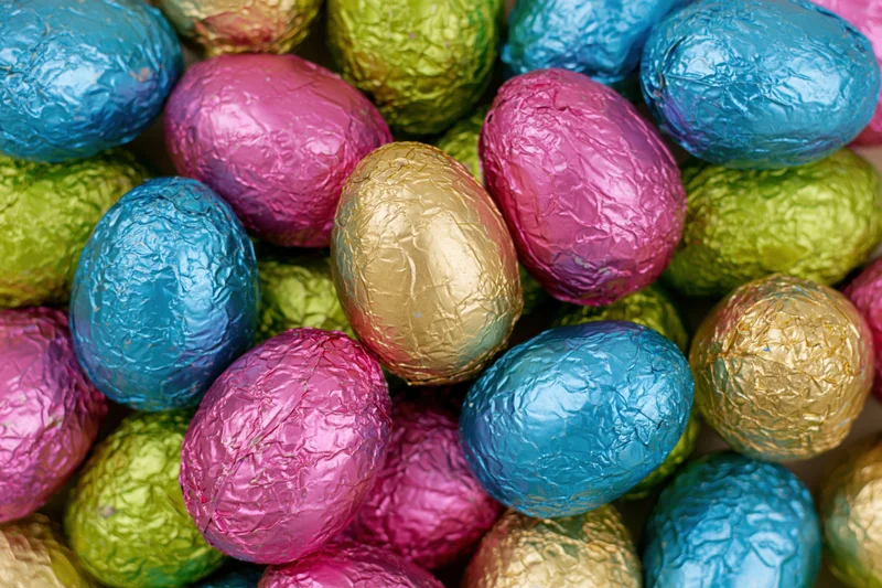Foil-wrapped chocolate easter eggs piled together in a close-up view