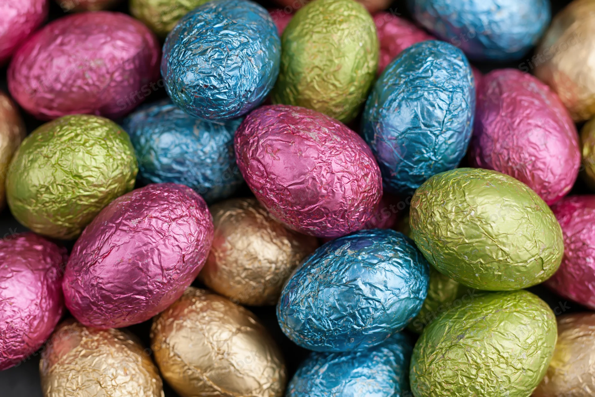 Foil-wrapped chocolate easter eggs piled together in a heap